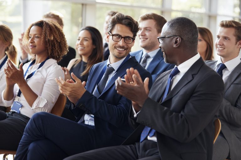 Audience clapping at business seminar, looking at each other