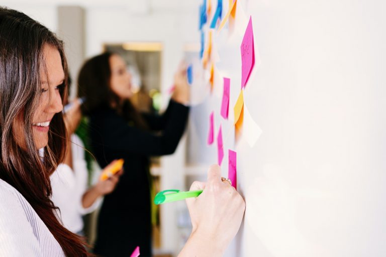 Businesswomen fixing sticky notes at office