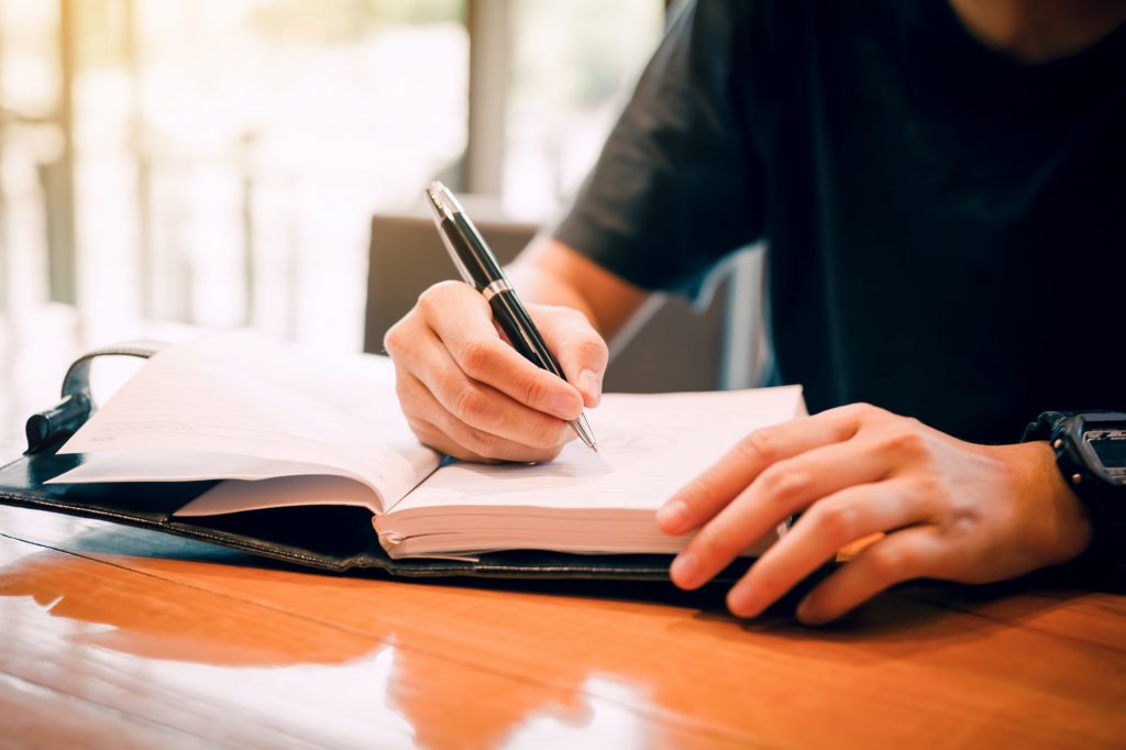 Young asian man hand writing on notebook.